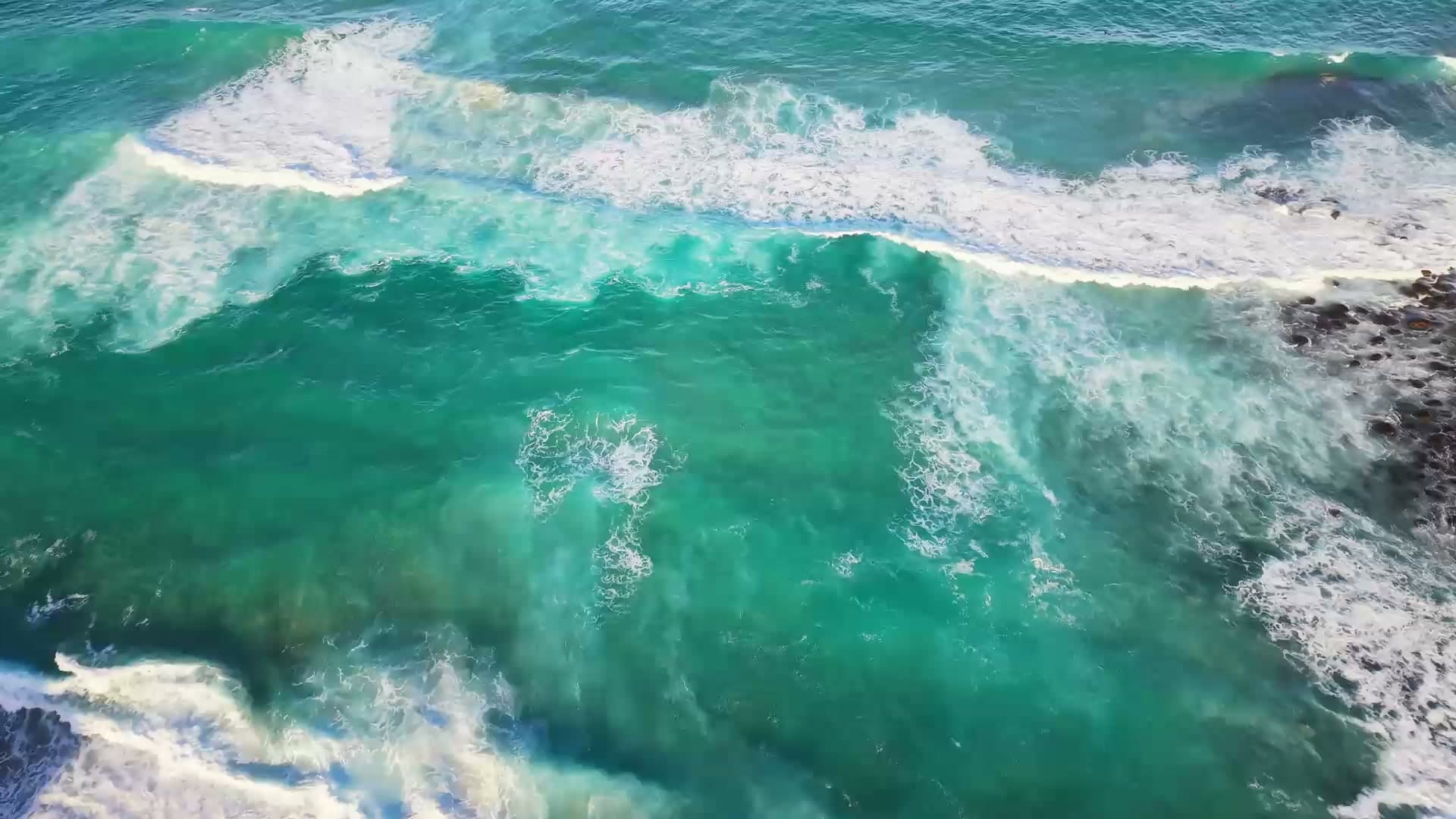 Aerial view of turquoise waves breaking along the Sydney coastline