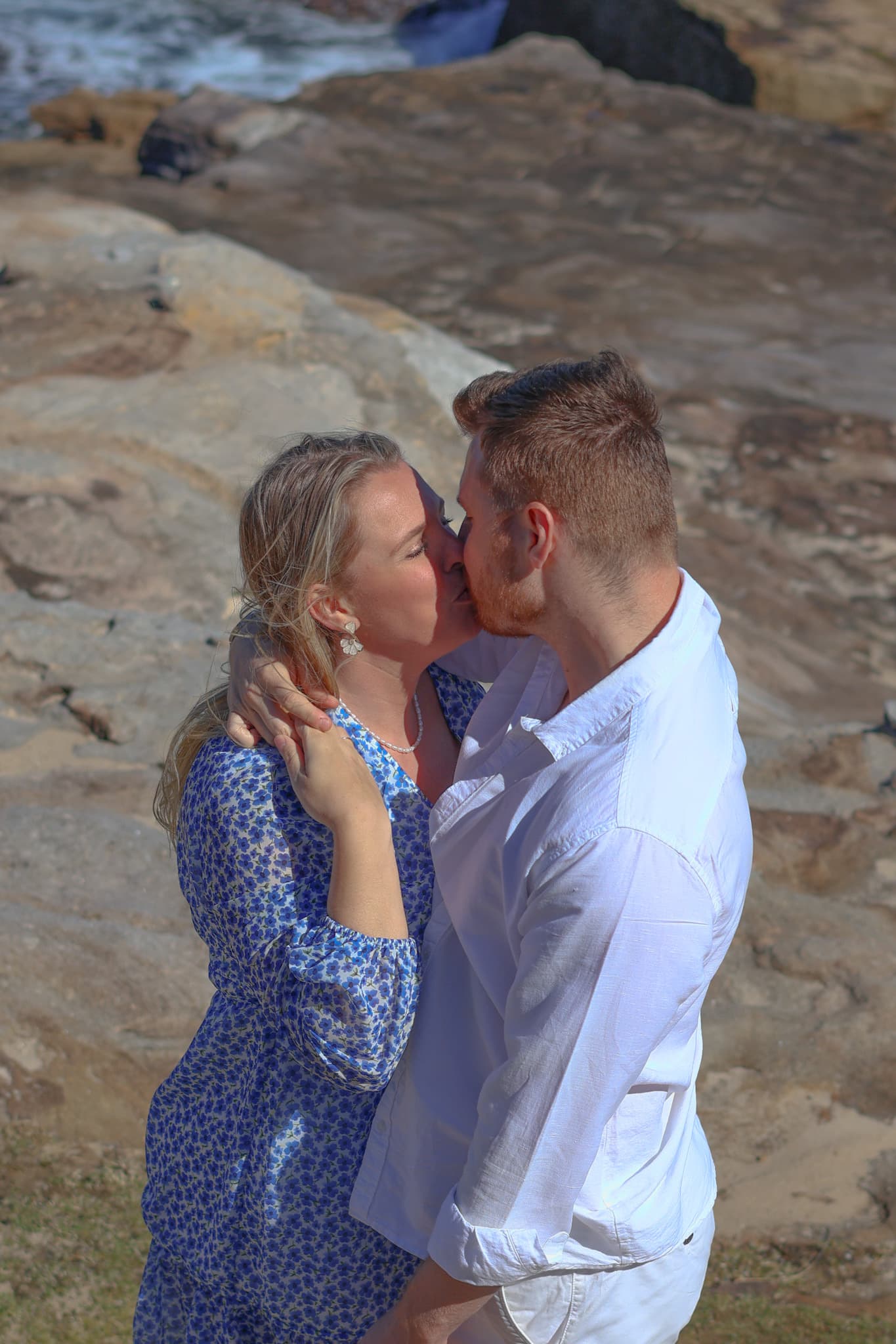 A couple walking along the shoreline at sunset during an engagement photo session